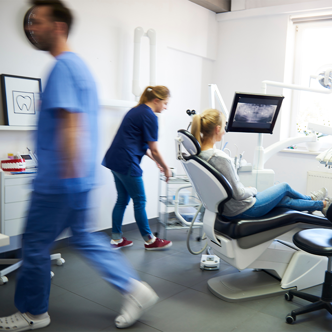Praxis mit Patient und Bildschirm, der eine Röntgenaufnahme des Mundes zeigt